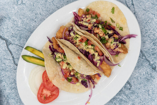 Overhead View Of Threesome Of Tempting Fish Tacos Loaded With All The Fillings To Satisfy Any Appetite For Mexican Food.