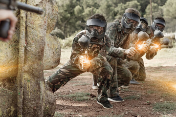 Expressive paintball team running with a marker guns on an open playing field