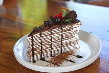Homemade sweet sliced chocolate crepes cake with Strawberry and Cookies close-up on a plate. selective focus
