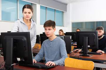 Fototapeta na wymiar Female teacher helping male student in computer class in university