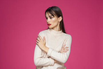 Obraz premium Brunette with long hair red lips cosmetics white sweater pink background cropped view