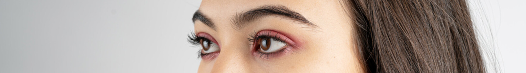 Fototapeta premium Macro shot of woman eye makeup with red eyeshadow. Close-up of woman eyelashes. Panoramic shot.