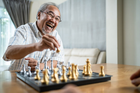 Close-up shot of Asian old man enjoy playing chess with friend.