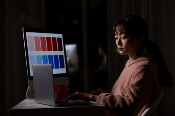 深夜に仕事をするパジャマ姿の若い女性