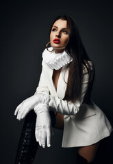 Rich sexy woman in white jacket, jabot frill, collar, gloves and high leather boots stands with her...