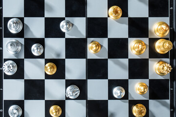 High angle shot of silver and golden chess pawns on the checkered board