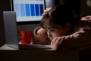 深夜に仕事をするパジャマ姿の若い女性