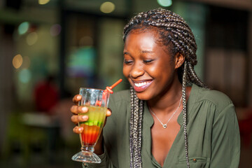 image of beautiful african lady, holding a glass of cocktail with excitement