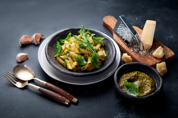 Pasta spaghetti with homemade pesto and fresh basil leaves on dark background. Italian cuisine concept.