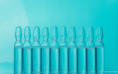Glass medical ampoule vial for injection. Medicine is liquid sodium chloride with of aqueous solution in ampulla. Close up. Bottles ampule multicolor.