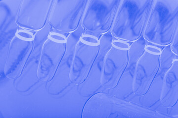 Glass medical ampoule vial for injection. Medicine is liquid sodium chloride with of aqueous solution in ampulla. Close up. Bottles ampule multicolor.