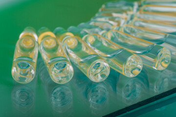 Glass medical ampoule vial for injection. Medicine is liquid sodium chloride with of aqueous solution in ampulla. Close up. Bottles ampule multicolor.