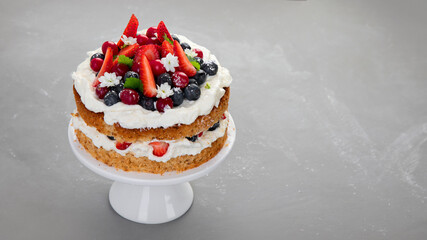 Delicious homemade cake with fresh berries and mascarpone cream on gray background.