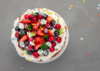 Delicious homemade cake with fresh berries and mascarpone cream on gray background.