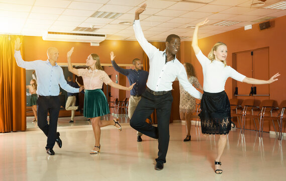 Young positive people dancing tap dance in pairs in studio..