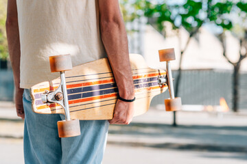 horizontal take of the detail of a skateboard hold by unrecognizable caucasian man. © dzmatph