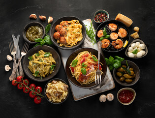 Assortment of Italian pasta with traditional sauces for dinner on dark background.