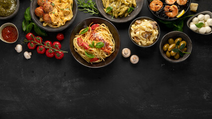 Assortment of Italian pasta with traditional sauces for dinner on dark background.