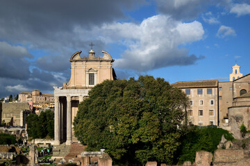 Fototapeta na wymiar cloudy cityscape over roman forum - Antoninus and Faustina Temple (now San Lorenzo in Miranda church) - Rome, Lazio, Italy
