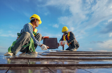 Roofer installing ceramic roof tile on top roof by using air pneumatic nail gun .Construction worker wearing safety harness belt during working on roof structure building in construction site - obrazy, fototapety, plakaty