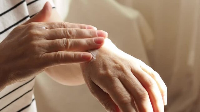 Hands of a mature woman, applying moisturizer to the skin. Anti-aging care at an older age.