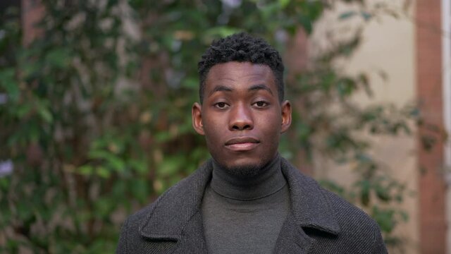 Portrait young black man standing outdoors looking at camera
