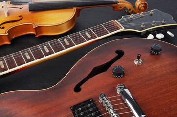 Fototapeta premium Two electric guitars and a violin on a dark background.