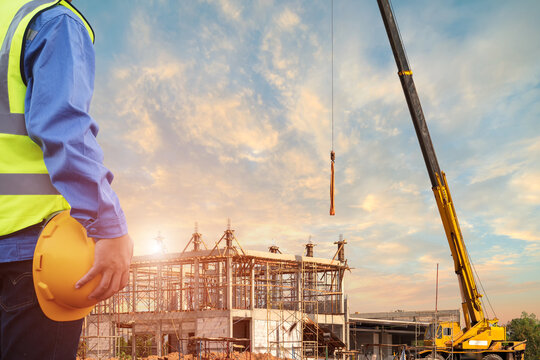 Engineering male construction worker holding yellow helmet wear reflective clothing for safety of the work operation.Construction engineering working outdoor building, cranes construction background