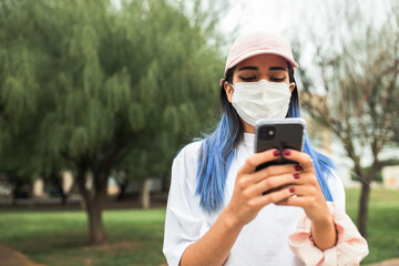 Mujer usando barbijo mientras escribe en su celular