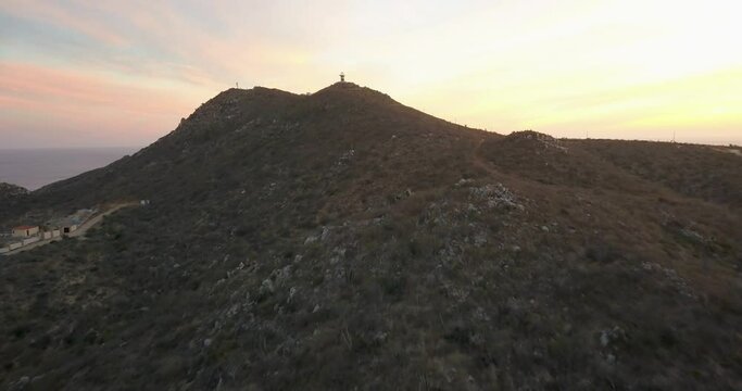 Aerial approaching modern lighthouse at Cabo Falso, Cabo San Lucas. Beautiful sunset tones.