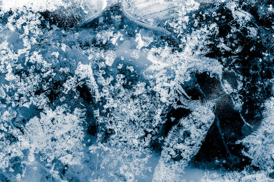 Ice texture background. Textured, blue tone, cold, frosty surface of ice block on black background.