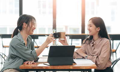 Two young asian women collide with coffee cups at office.