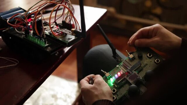 DIY, the machine on electronic control. Home experiments, robotics, smart engineer. Toy for the child. The man controls the electronic device from the radio desk. motherboard.