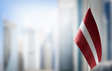 A small flag of Latvia on the background of a blurred background - obrazy, fototapety, plakaty
