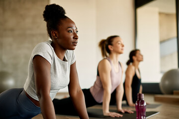 African American athletic woman stretching during exercise class at health club. - Powered by Adobe