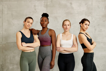Portrait of confident diverse female athletes against the wall looking at camera.