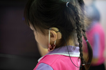 Students sitting and doing exercises in the classroom. child girl wearing a hearing aid.