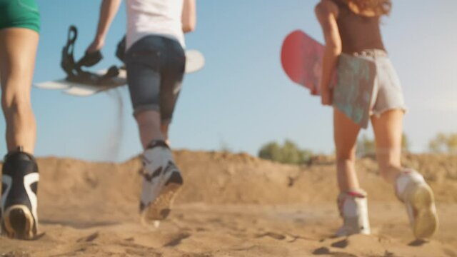 Three hipsters enjoying summer vacation. Adventure atmosphere. Young people guys with sandboard in hands running high at shining sunset. Holidays, sport, journey, travel, happiness, friendship concept