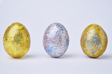 Golden and silver shiny painted eggs on white background.