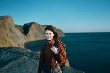 Fototapeta na wymiar cheerful woman with backpack on nature rocky mountains horizon ocean freedom