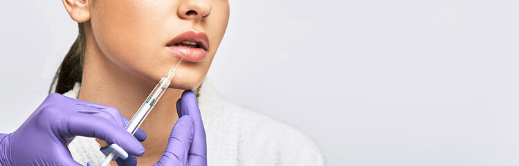 Lip augmentation. Cropped sensual female lips while procedure lip augmentation using injections...