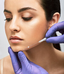 Mesothreads facial. Face contour lifting procedure, a needle with mesothreads near a female face,...