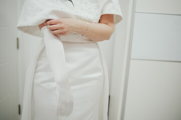 Unrecognizable woman with a white evening or wedding dress putting on opera gloves