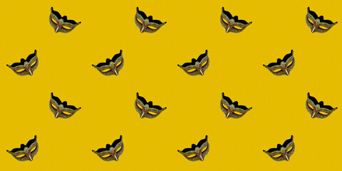 Classic Venetian theatrical mask isolated on a yellow background. Seamless texture of a repeating pattern. Wallpaper design concept.