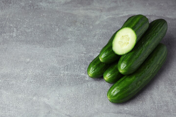 Ripe cucumbers on gray background, space for text