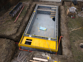 aerial drone shot of construction site from pool with formwork for concrete and finished brick wall from above