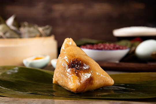 Closeup of zongzi on leaves on the table with ingredients on a blurry background