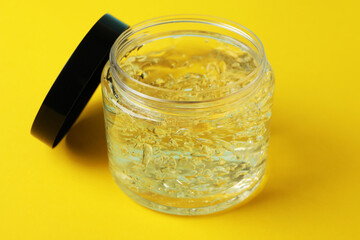 Jar of styling gel on yellow background, close up