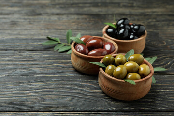 Bowls of different olives on wooden background