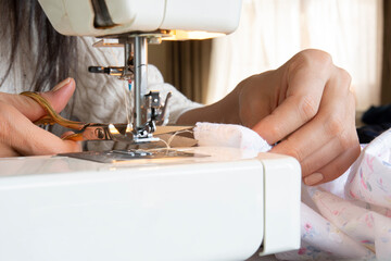 young woman putting thread on needle of sewing machine